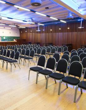 100 chairs in a large room with wooden floors.