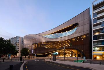 The exterior of Tākina at sunset, with orange lights shining through the glass.