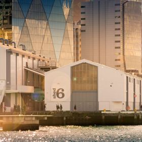 Looking across the waterfront at Shed 6, a building on the Queens Whard with large doors and the Shed 6 sign.