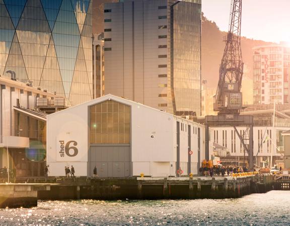 Looking across the waterfront at Shed 6, a building on the Queens Whard with large doors and the Shed 6 sign.