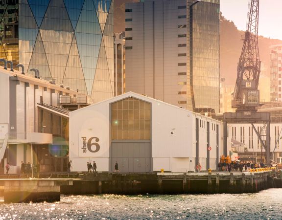Looking across the waterfront at Shed 6, a building on the Queens Whard with large doors and the Shed 6 sign.