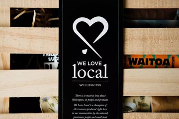 Wooden box with slats partially revealing its contents and a black label with a heart illustration and white text.