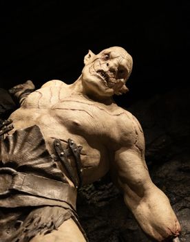 A life size Orc statue from Lord of the Rings pulls a weapon over its shoulder.