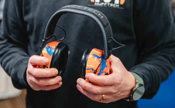 Close up of Mufftech’s orange roughy bluetooth earmuffs.