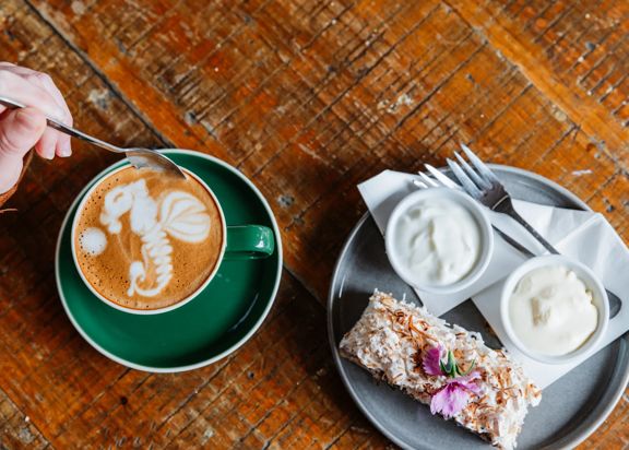 Latte art and a dessert on a table.