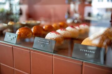 A line of Raspberry Bombolini's and other sweet treats in a food cabinet at August Eatery in Wellington.