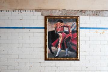 A framed painting of a bullfighter in traditional red garb.