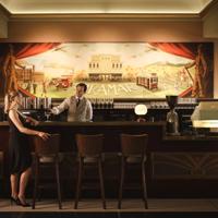 The bar at Roxy Cinema in Miramar, Wellington. A patron in a black dress is waiting while a bartender pours a drink.