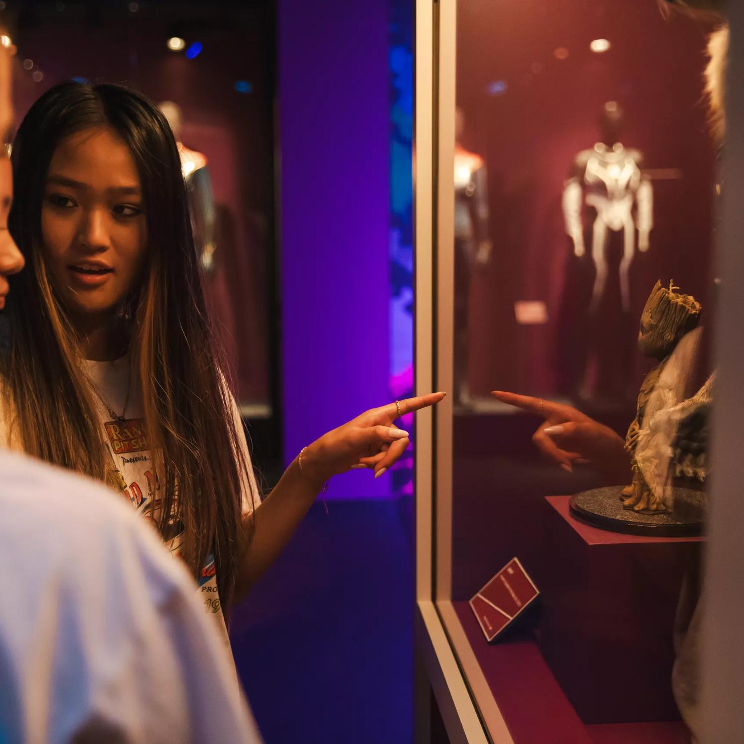 Three people are looking at a Groot statue on display at Marvel:Earth's Mightiest Exhibition.