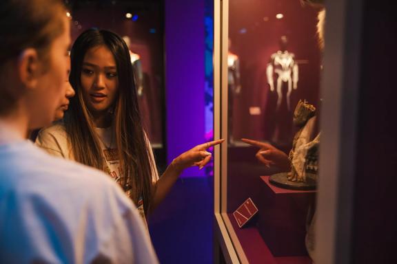 Three people are looking at a Groot statue on display at Marvel:Earth's Mightiest Exhibition.