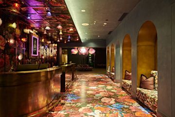 Naumi Hotel lobby interior with a floral carpet, wallpaper design, giant flower chair in the background.