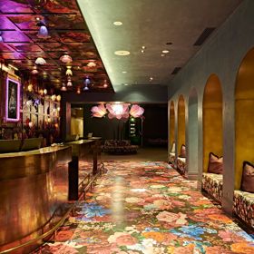 Naumi Hotel lobby interior with a floral carpet, wallpaper design, giant flower chair in the background.