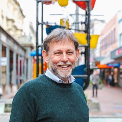 Headshot of David Wilks, a board member of WellingtonNZ, smiling in front of the Bucket Fountain.