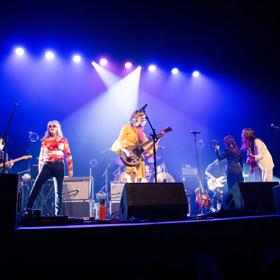 Atomic! 2.0, an all-female tribute band, performs on stage under purple spotlights.