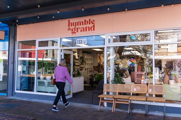 Person walking into Humble & Grand, with its peachy pink exterior and chairs sat outside.