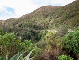 The screen location of Remutaka Summit, wit views of surrounding peaks, lush green bush and steep roads cut into the sides of the mountains.