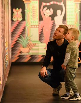A parent and child stare at an art installation inside the City Gallery.