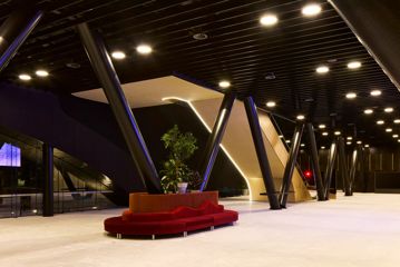 Inside the Tākina lobby, a red velvet sofa wraps around one of the large poles in the centre of the room, and an escalator makes its way upstairs.