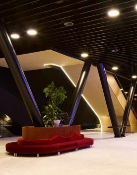 Inside the Tākina lobby, a red velvet sofa wraps around one of the large poles in the centre of the room, and an escalator makes its way upstairs.