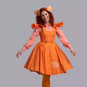 Emma Memma dressed in orange with orange hair smiling against a grey background.