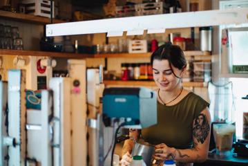 A barista making a coffee at Maranui Café.