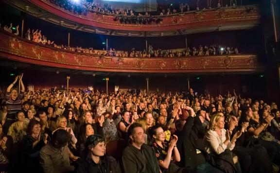 A packed audience cheering and applauding at The Opera House in Te Aro, Wellington.