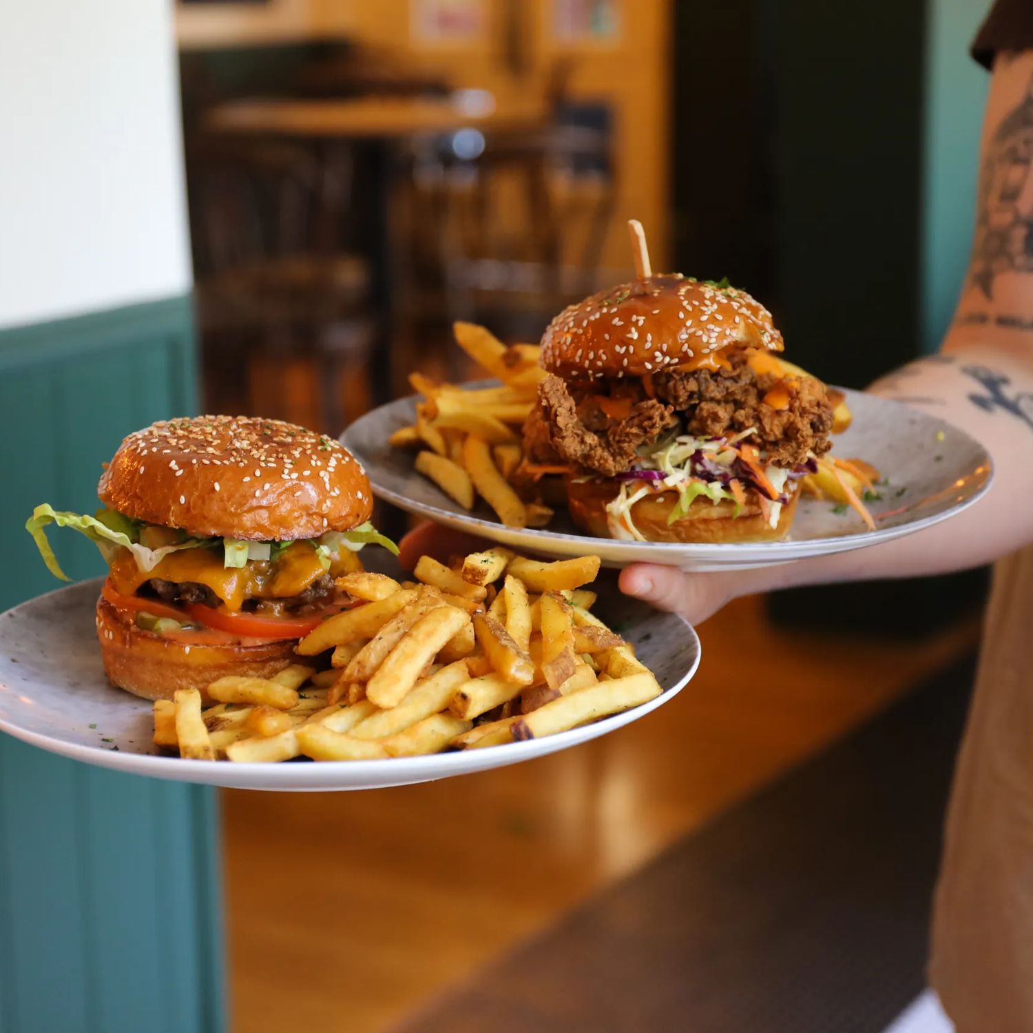 Server carrying two plates with burgers and fries at The Junction in Wellington.
