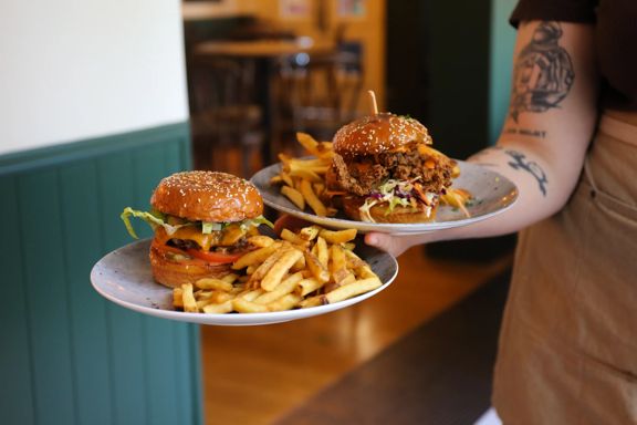 Server carrying two plates with burgers and fries at The Junction in Wellington.