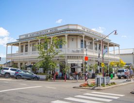 Exterior shot of The Martinborough Hotel, a Victorian era building surrounded by trees and pedestrians.