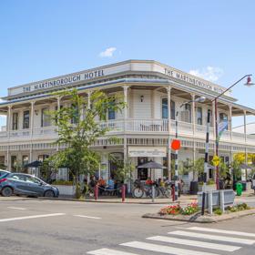 Exterior shot of The Martinborough Hotel, a Victorian era building surrounded by trees and pedestrians.