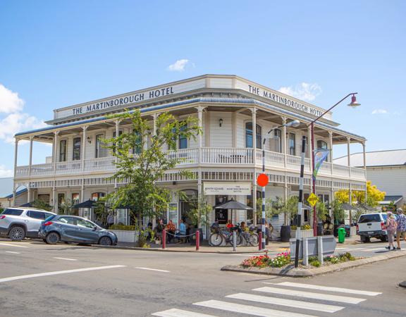 Exterior shot of The Martinborough Hotel, a Victorian era building surrounded by trees and pedestrians.