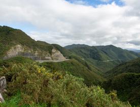 The screen location of Remutaka Summit, wit views of surrounding peaks, lush green bush and steep roads cut into the sides of the mountains.