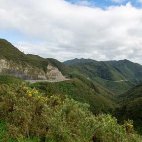 The screen location of Remutaka Summit, wit views of surrounding peaks, lush green bush and steep roads cut into the sides of the mountains.