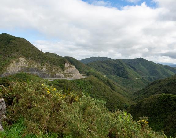 The screen location of Remutaka Summit, wit views of surrounding peaks, lush green bush and steep roads cut into the sides of the mountains.