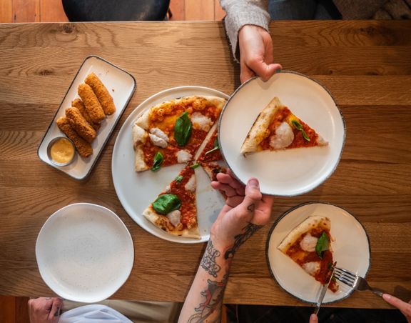A Margherita pizza being shared and mozzarella sticks.