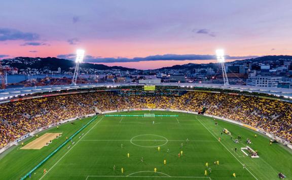 A football match at Wellington Stadium during sunset with a pink blue coloured sky