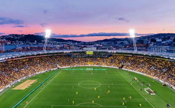 A football match at Wellington Stadium during sunset with a pink blue coloured sky