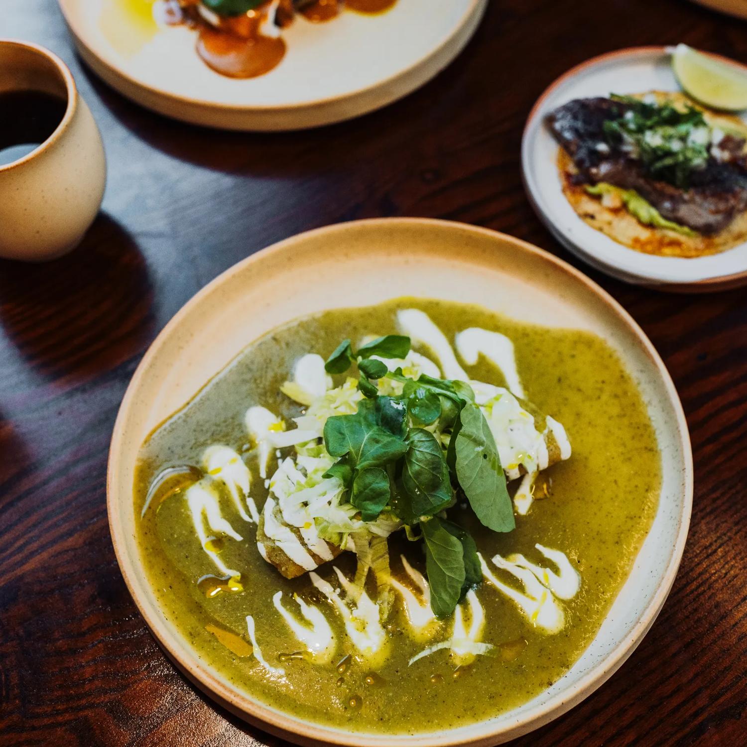 A taco dish with green and white sauce and a leafy garnish at Apapacho.