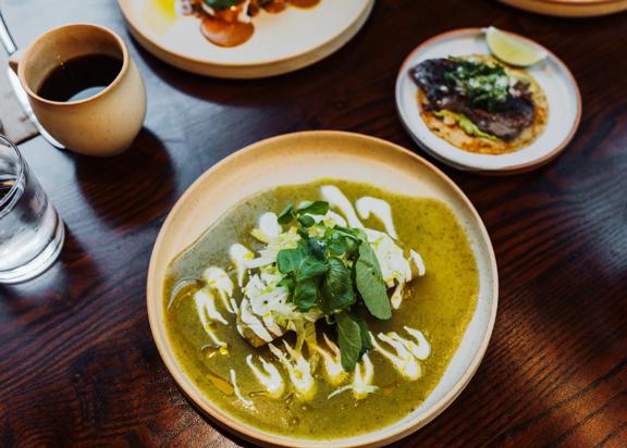 A taco dish with green and white sauce and a leafy garnish at Apapacho.