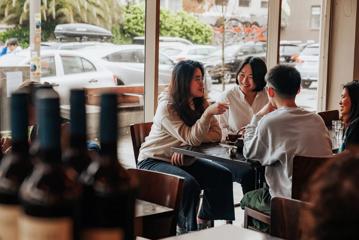 4 people enjoying hot drinks and pastries inside Floriditas.