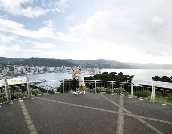 Two people take a selfie together at the Mount Victoria Lookout overlooking Wellington.