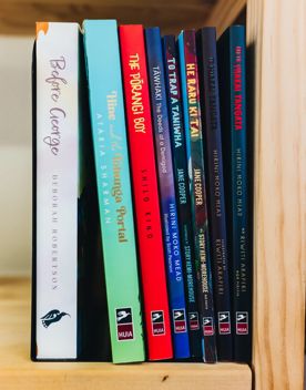 Te Reo Maori books stacked in a bookshelf with the Huia Publisher logo on the spine.