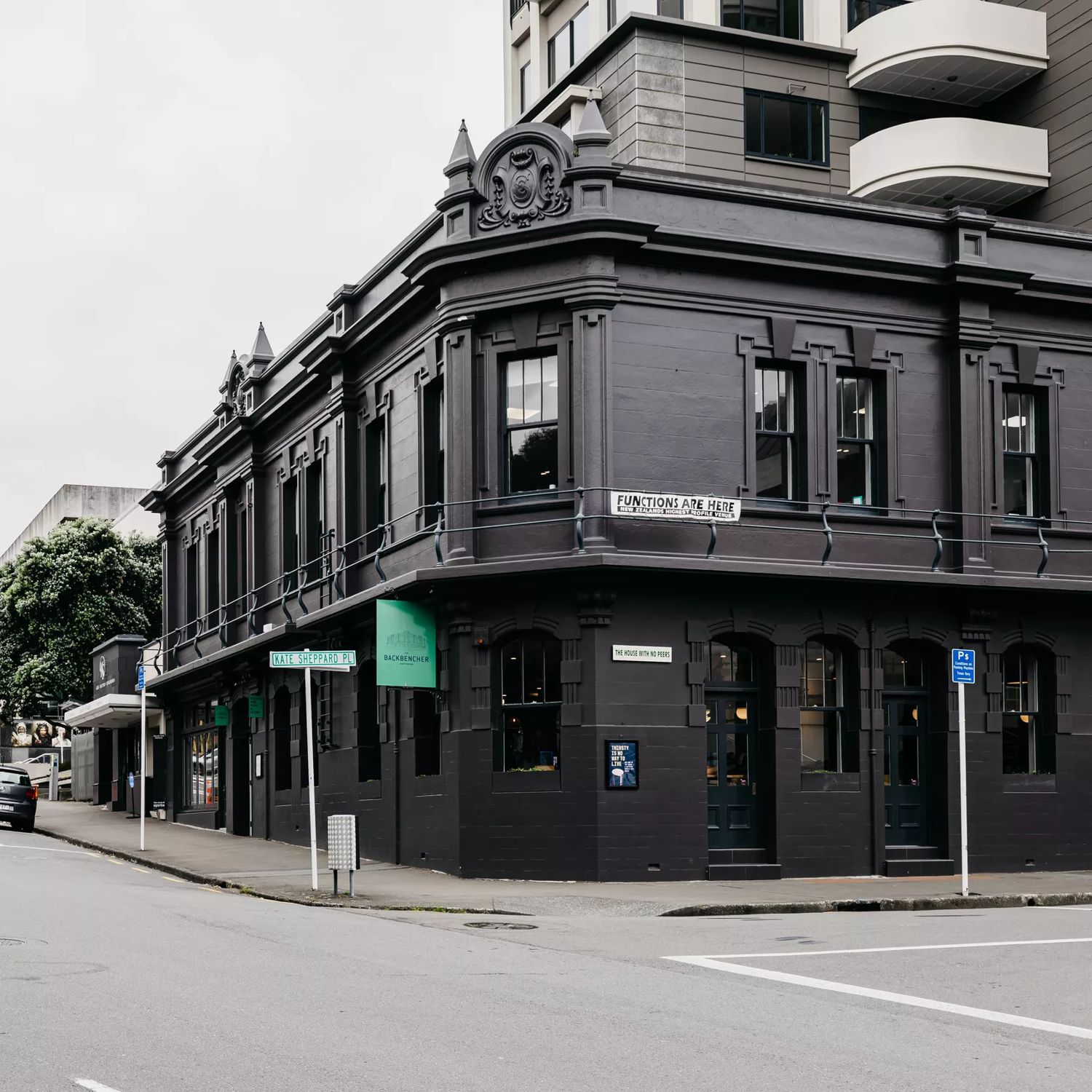 The exterior of The Backbencher Gastropub is housed inside a two-storey, black, Victorian-era style building.