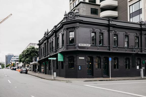 The exterior of The Backbencher Gastropub is housed inside a two-storey, black, Victorian-era style building. 