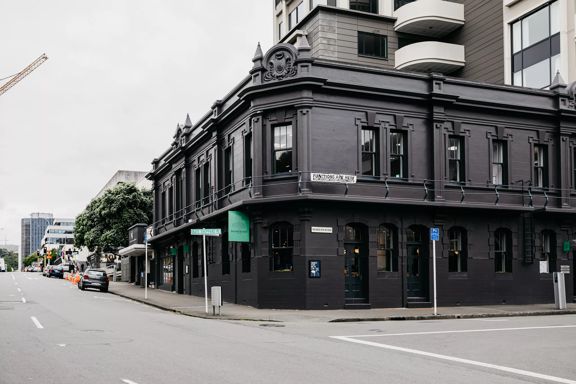 The exterior of The Backbencher Gastropub is housed inside a two-storey, black, Victorian-era style building.