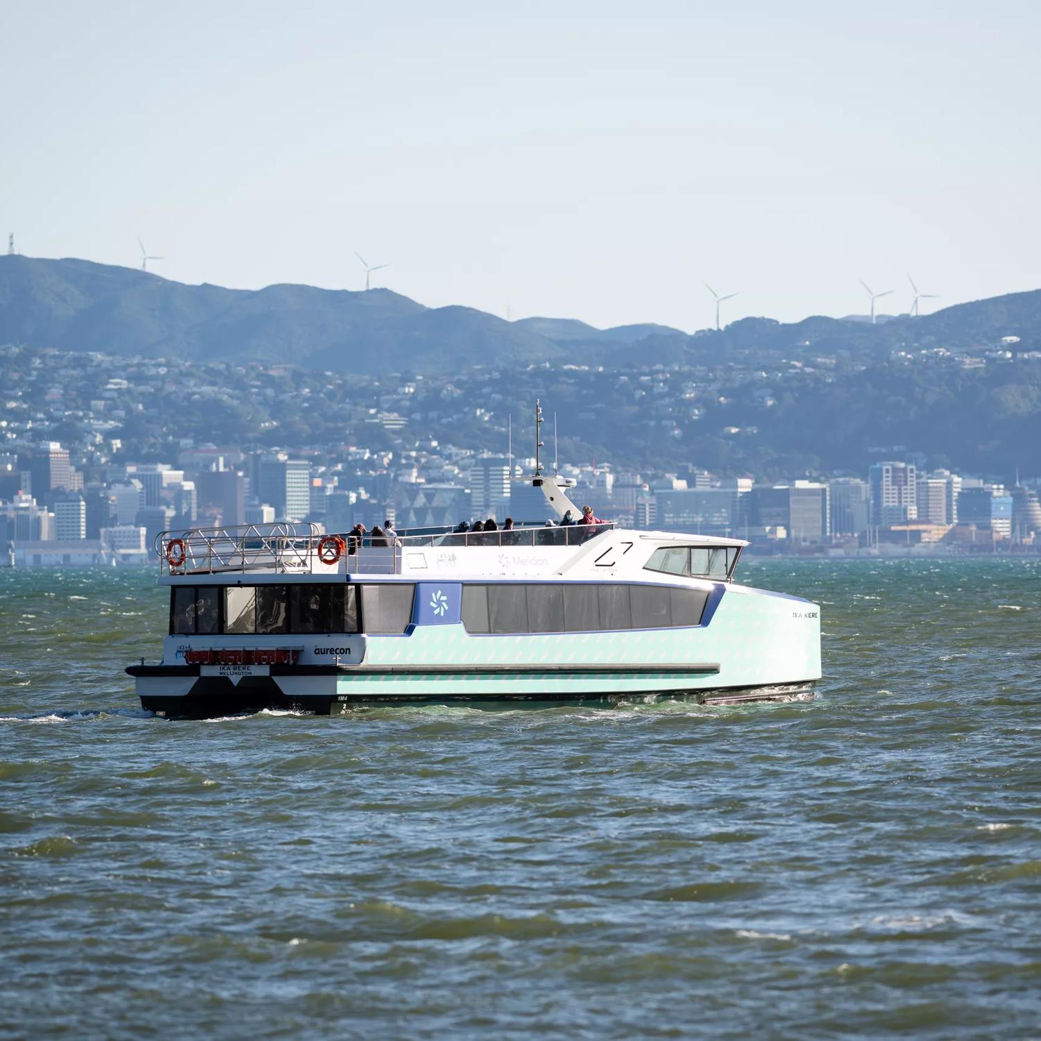 The East by West Ferry on the water with the Wellington skyline and hills in the background.