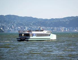 The East by West Ferry on the water with the Wellington skyline and hills in the background.