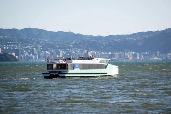 The East by West Ferry on the water with the Wellington skyline and hills in the background.