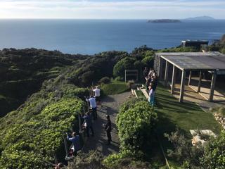 People in shooting range over bush, overlooking the ocean, Kāpati and Mana islands.