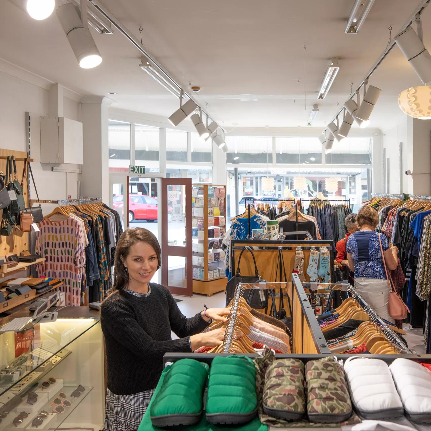 Inside the Wanda Harland store in Petone. It has a glass front with the sun shining in the store. Racks of clothing line the walls.